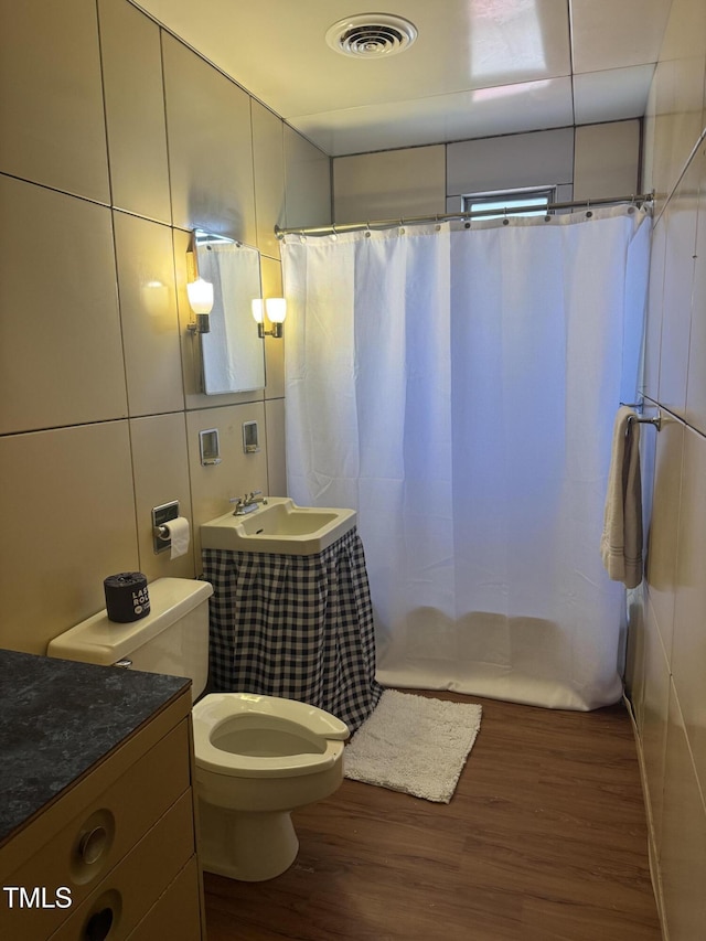 bathroom with wood finished floors, toilet, vanity, and shower / tub combo