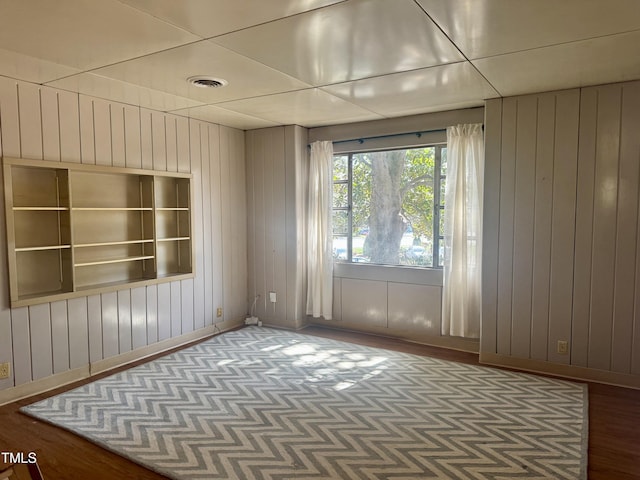 unfurnished room featuring wooden walls, baseboards, and wood finished floors