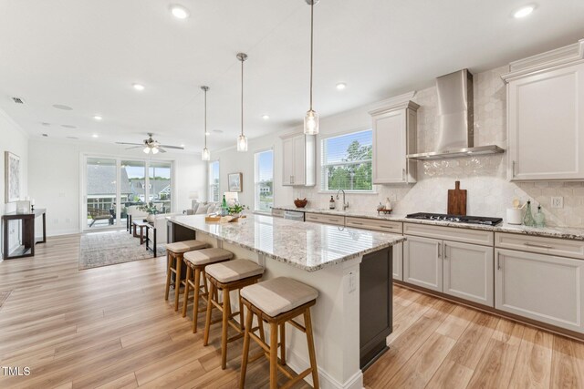 1625 Plover Cir, Fuquay Varina, NC 27526 - kitchen featuring wall chimney exhaust hood, stainless steel gas cooktop, light wood-type flooring, tasteful backsplash, and recessed lighting
