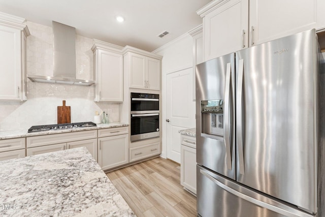 1625 Plover Cir, Fuquay Varina, NC 27526 - kitchen featuring appliances with stainless steel finishes, wall chimney range hood, light wood-style floors, tasteful backsplash, and crown molding
