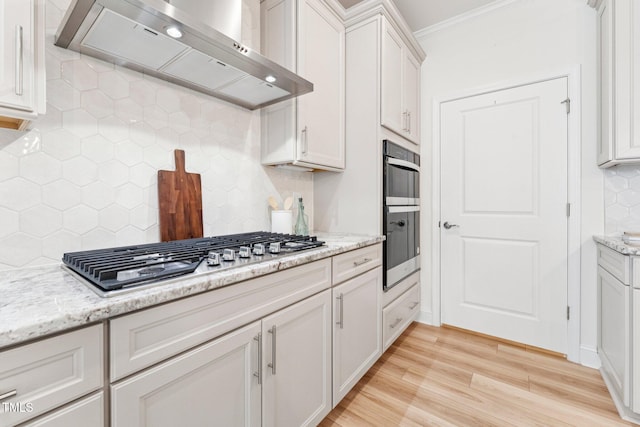 1625 Plover Cir, Fuquay Varina, NC 27526 - kitchen featuring wall chimney range hood, stainless steel appliances, tasteful backsplash, light wood-style flooring, and white cabinetry