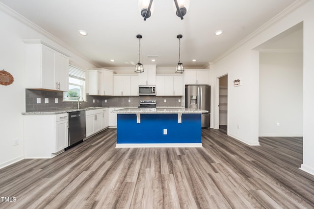 171 Piney Field Rd, Fuquay Varina, NC 27526 - kitchen featuring stainless steel appliances, a kitchen island, wood finished floors, a breakfast bar area, and crown molding