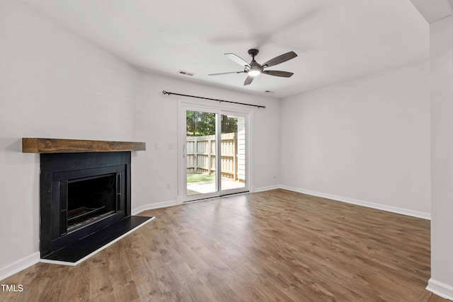 129 Assembly Ct, Cary, NC 27511 - unfurnished living room with a ceiling fan, wood finished floors, a fireplace with raised hearth, and baseboards