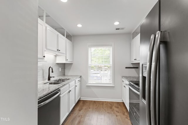 129 Assembly Ct, Cary, NC 27511 - kitchen featuring stainless steel appliances, a sink, tasteful backsplash, light stone counters, and white cabinetry