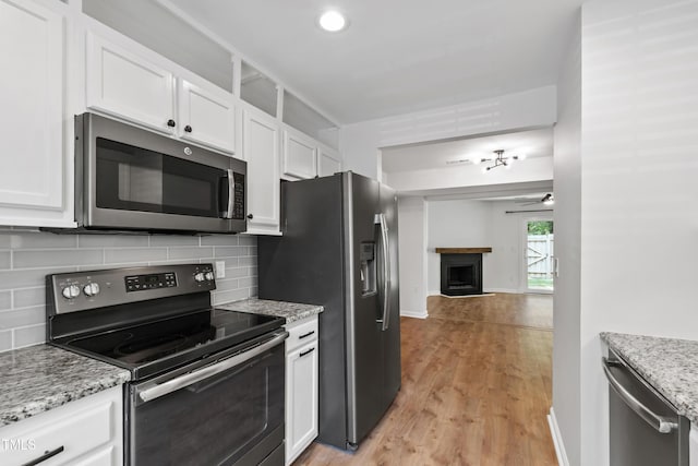 129 Assembly Ct, Cary, NC 27511 - kitchen with appliances with stainless steel finishes, decorative backsplash, white cabinets, a fireplace, and recessed lighting