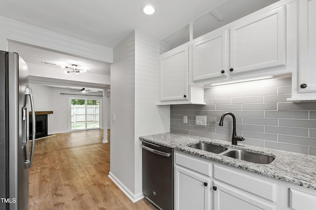 129 Assembly Ct, Cary, NC 27511 - kitchen featuring stainless steel appliances, a sink, tasteful backsplash, white cabinets, and light wood-style flooring