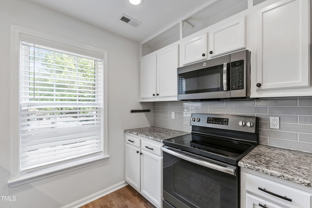 129 Assembly Ct, Cary, NC 27511 - kitchen with appliances with stainless steel finishes, white cabinets, backsplash, wood finished floors, and light stone counters