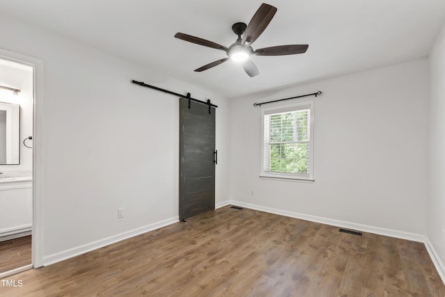 129 Assembly Ct, Cary, NC 27511 - unfurnished bedroom featuring a barn door, light wood-style flooring, and baseboards