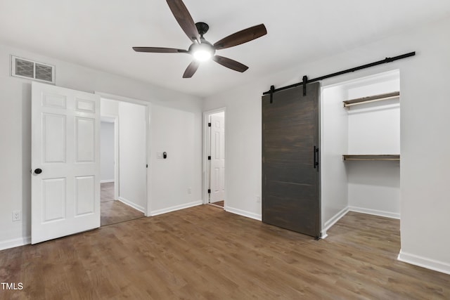 129 Assembly Ct, Cary, NC 27511 - unfurnished bedroom featuring wood finished floors, a barn door, baseboards, and a spacious closet