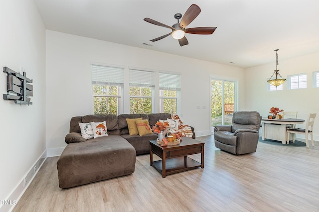 living room with wood finished floors, healthy amount of natural light, a ceiling fan, and baseboards