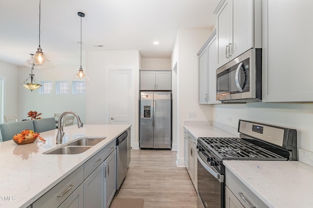 kitchen with appliances with stainless steel finishes, a sink, gray cabinets, light wood finished floors, and recessed lighting
