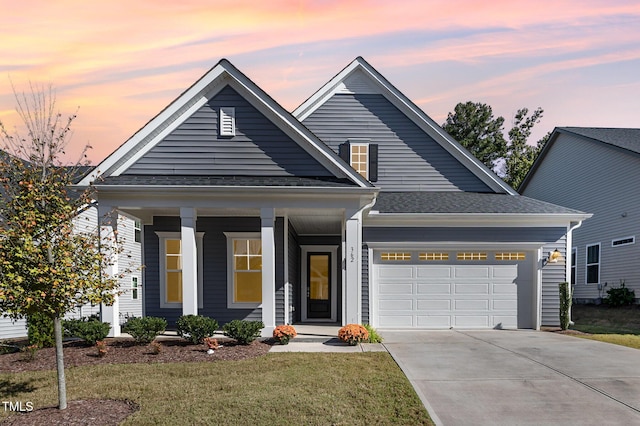 view of front of home with an attached garage, driveway, covered porch, a yard, and roof with shingles