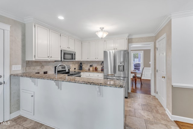 2721 Dahlgreen Rd, Raleigh, NC 27615 - kitchen featuring stainless steel appliances, light stone counters, a peninsula, white cabinetry, and crown molding