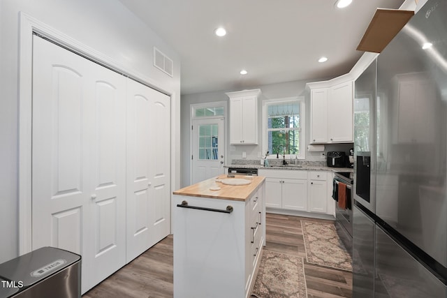 2620 Holloway St, Durham, NC 27703 - kitchen featuring appliances with stainless steel finishes, wooden counters, recessed lighting, wood finished floors, and white cabinets