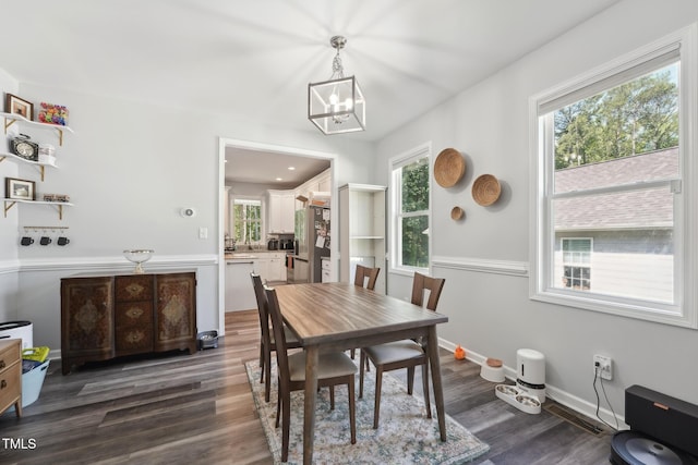 2620 Holloway St, Durham, NC 27703 - dining room with a chandelier, dark wood-type flooring, and baseboards