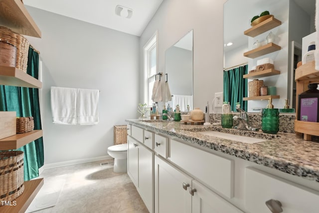 2620 Holloway St, Durham, NC 27703 - full bathroom with double vanity, baseboards, toilet, and vaulted ceiling