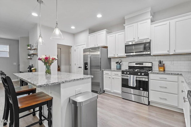 320 Everly Mist Way, Wake Forest, NC 27587 - kitchen featuring appliances with stainless steel finishes, a kitchen island, white cabinetry, backsplash, and light stone countertops