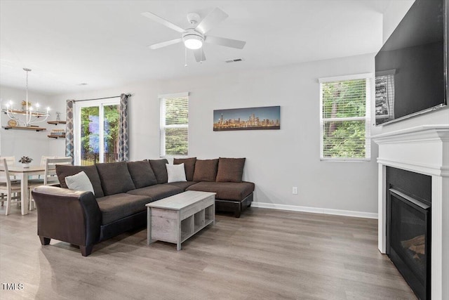 320 Everly Mist Way, Wake Forest, NC 27587 - living room with a chandelier, a glass covered fireplace, light wood-style floors, baseboards, and ceiling fan