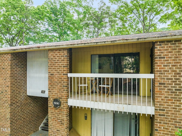 doorway to property featuring brick siding and a balcony