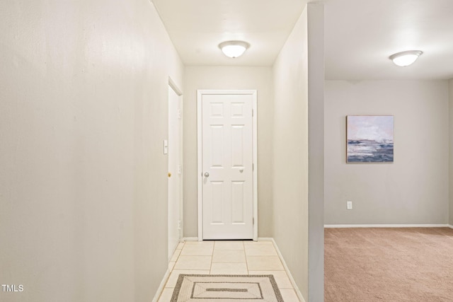 hallway with baseboards and light colored carpet