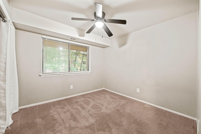 carpeted spare room featuring ceiling fan and baseboards