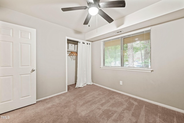 unfurnished bedroom with carpet flooring, baseboards, a closet, and a ceiling fan