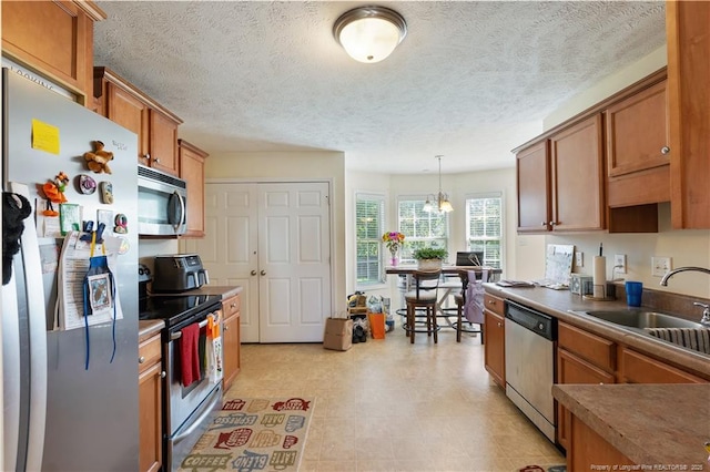 9012 Grouse Run Ln, Fayetteville, NC 28314 - kitchen featuring appliances with stainless steel finishes, a sink, brown cabinets, decorative light fixtures, and a textured ceiling