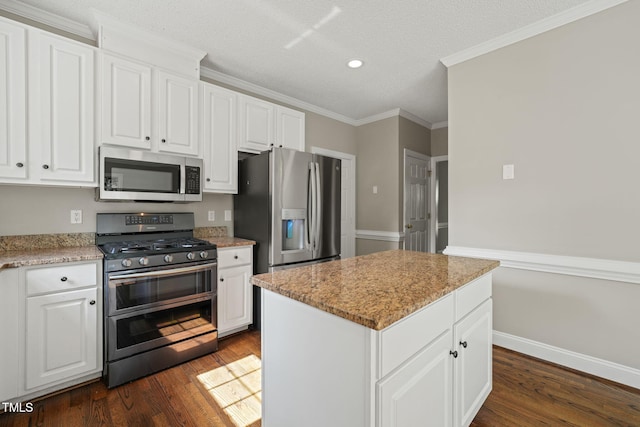 1005 Barmkin Pl, Knightdale, NC 27545 - kitchen with appliances with stainless steel finishes, dark wood finished floors, white cabinets, ornamental molding, and recessed lighting