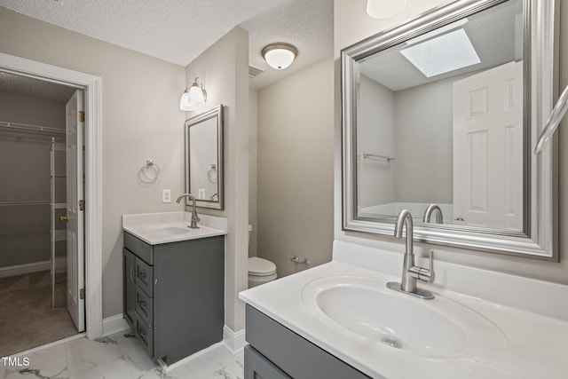 1005 Barmkin Pl, Knightdale, NC 27545 - bathroom with marble finish flooring, a skylight, two vanities, a spacious closet, and a textured ceiling