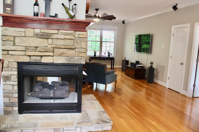 3750 Mebane Rogers Rd, Mebane, NC 27302 - detailed view of ceiling fan, crown molding, a stone fireplace, wood finished floors, and baseboards