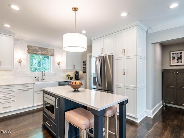 2303 Byrd St, Raleigh, NC 27608 - kitchen featuring appliances with stainless steel finishes, a sink, a kitchen bar, crown molding, and white cabinets