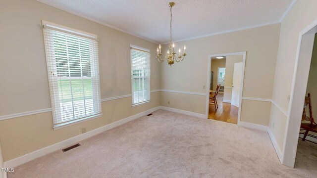 spare room featuring a chandelier, crown molding, carpet, baseboards, and a textured ceiling