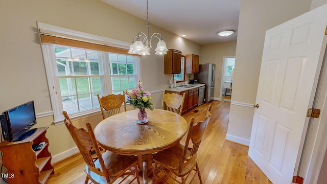 dining space featuring light wood-style floors, a chandelier, and baseboards
