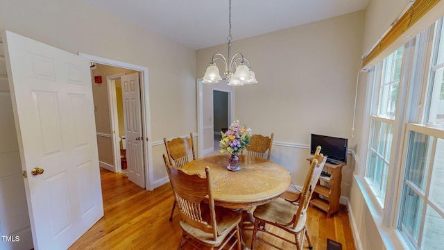 dining area with light wood-style flooring, a chandelier, and baseboards