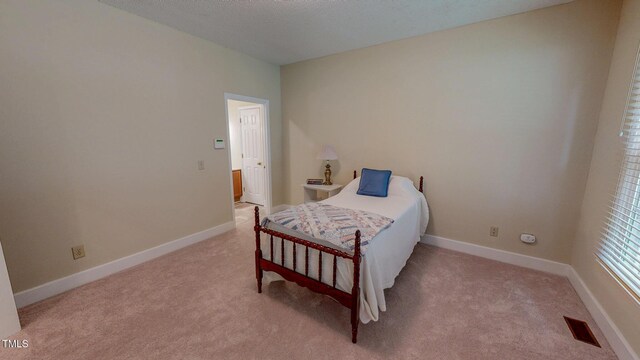 bedroom with light colored carpet and baseboards