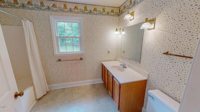 full bathroom featuring toilet, baseboards, vanity, and shower / bath combo with shower curtain