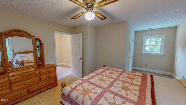 bedroom with light colored carpet, a textured ceiling, baseboards, and a ceiling fan