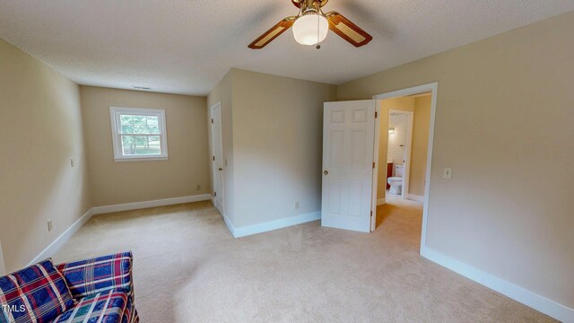 unfurnished bedroom featuring light carpet, baseboards, a ceiling fan, and a textured ceiling