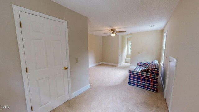 sitting room featuring light carpet, a ceiling fan, and baseboards
