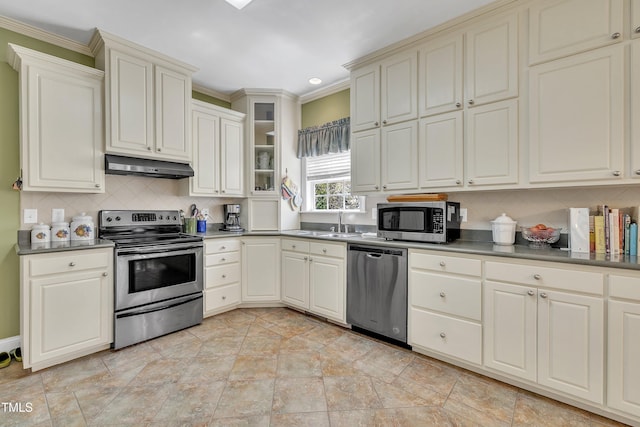 107 Stargrass Ave, Clayton, NC 27527 - kitchen with stainless steel appliances, under cabinet range hood, tasteful backsplash, ornamental molding, and cream cabinetry
