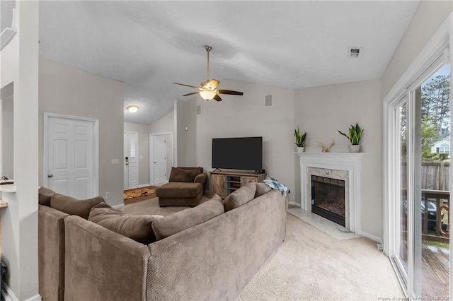 living area with a fireplace, ceiling fan, baseboards, lofted ceiling, and light carpet