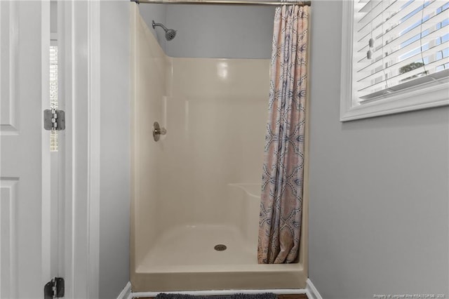 bathroom featuring baseboards, plenty of natural light, and a shower stall