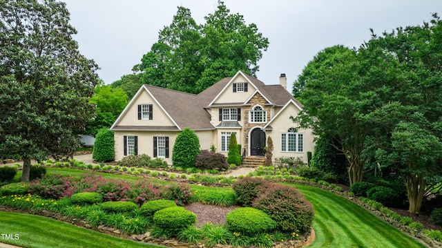 608 Greyrock Rd, Whitsett, NC 27377 - traditional-style home featuring stucco siding, a chimney, stone siding, and a front yard