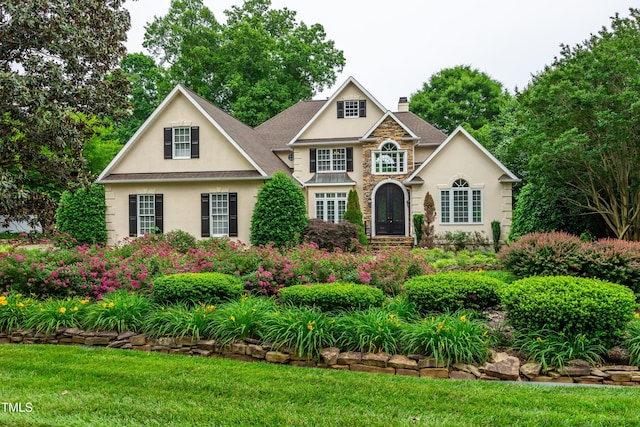 608 Greyrock Rd, Whitsett, NC 27377 - view of front of home with a chimney, stucco siding, stone siding, and a front lawn