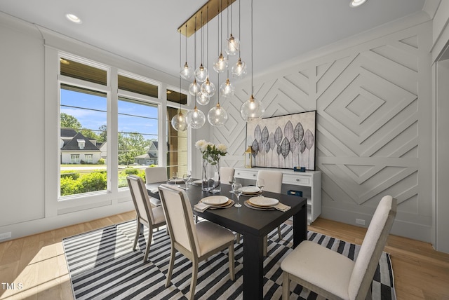 dining area with a decorative wall, light wood-style floors, and recessed lighting