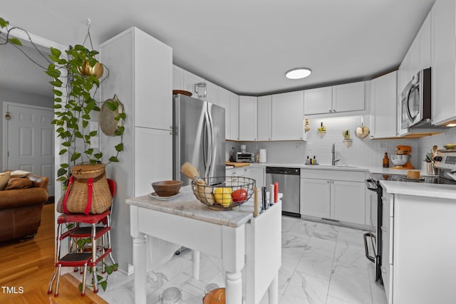 kitchen with stainless steel appliances, a sink, light countertops, and white cabinetry