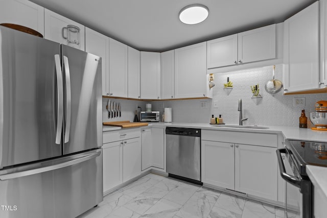 kitchen featuring appliances with stainless steel finishes, light countertops, light marble finish floors, and a sink