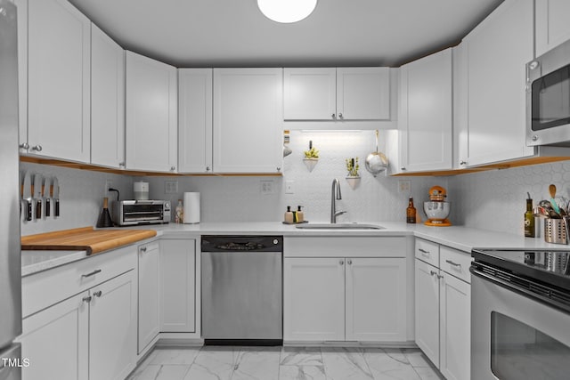 kitchen with stainless steel appliances, a sink, light countertops, and light marble finish flooring
