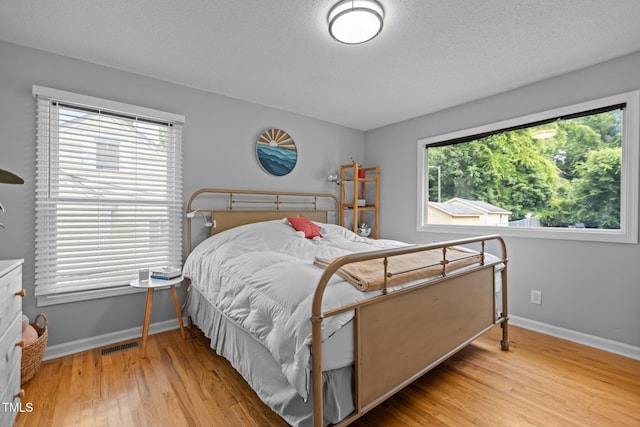 bedroom featuring wood finished floors, baseboards, and a textured ceiling