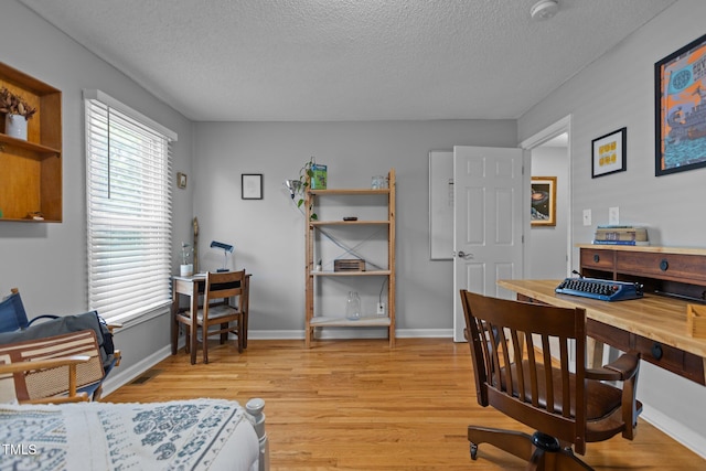 office space with light wood finished floors, a textured ceiling, and baseboards